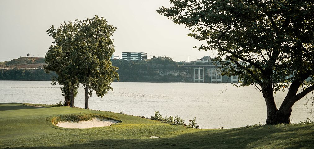 A golf green on the shoreline at Lake of the Ozarks, Missouri, with the bridge in the distance