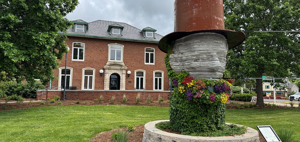 A brick civic building in Macomb, Illinois, with a flower-planted top hat sculpture out front